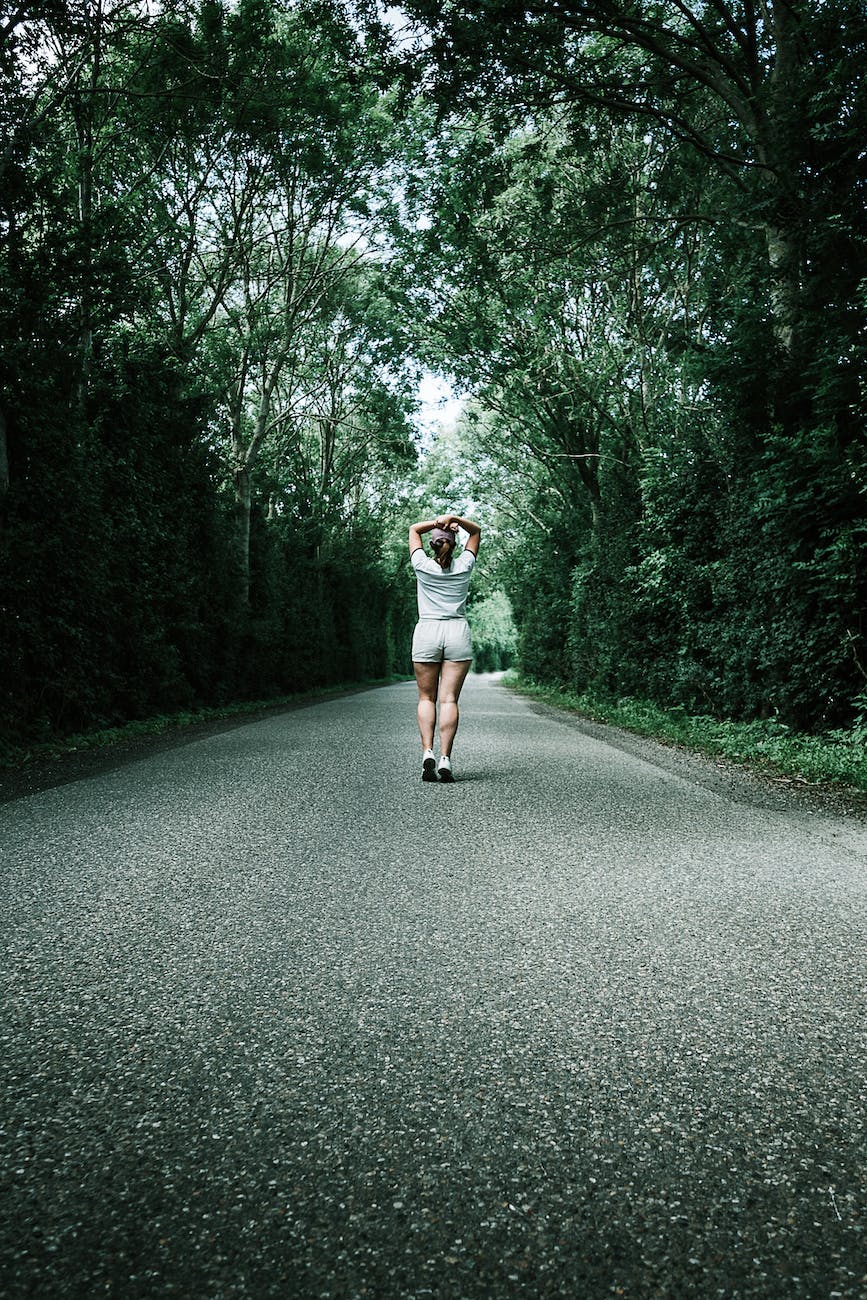 woman in white t shirt walking on concrete road