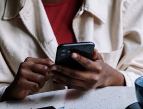 woman in white button up shirt holding black smartphone