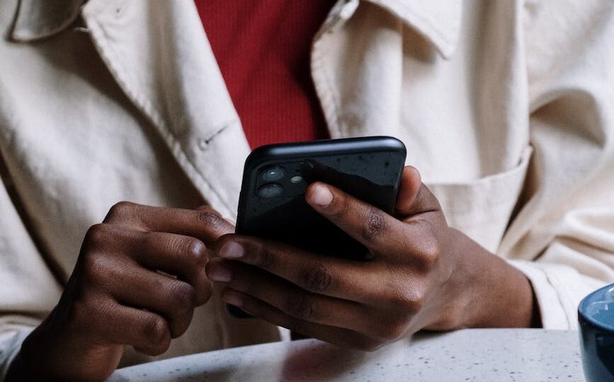 woman in white button up shirt holding black smartphone
