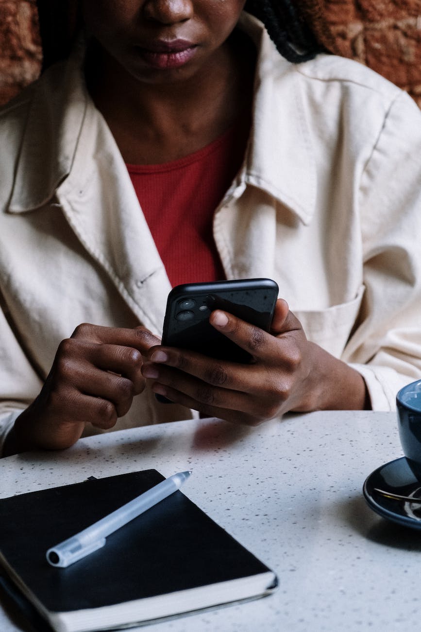 woman in white button up shirt holding black smartphone